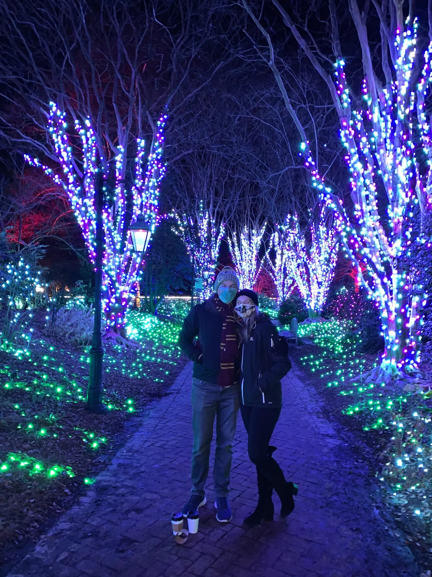 Jay and Gabi standing together under colorful winter lights.